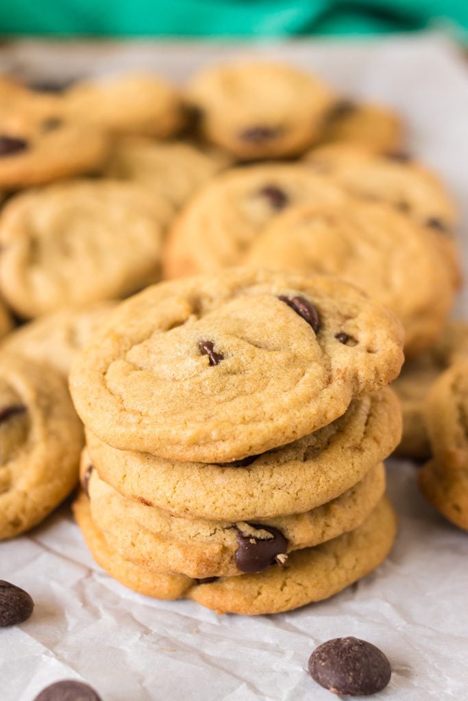 stack of 4 chocolate chip cookies surrounded by more cookies.