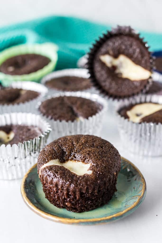 chocolate cupcake filled with cheesecake on a plate.
