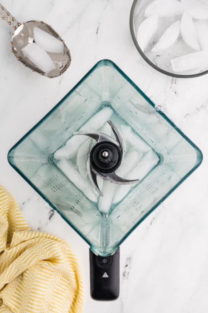 A blender filled with ice and lemon juice, ready to be blended.