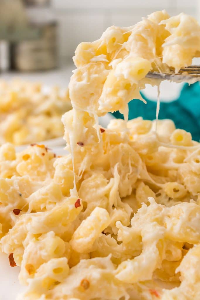 fork lifting a bite of cheesy mac & cheese from a plate.