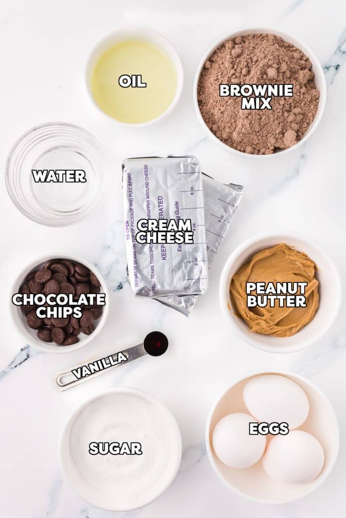 overhead shot of labeled ingredients laid out to make peanut butter brownie cheesecake.