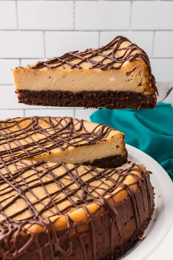 slice of brownie bottom peanut butter cheesecake being lifted from the cake.