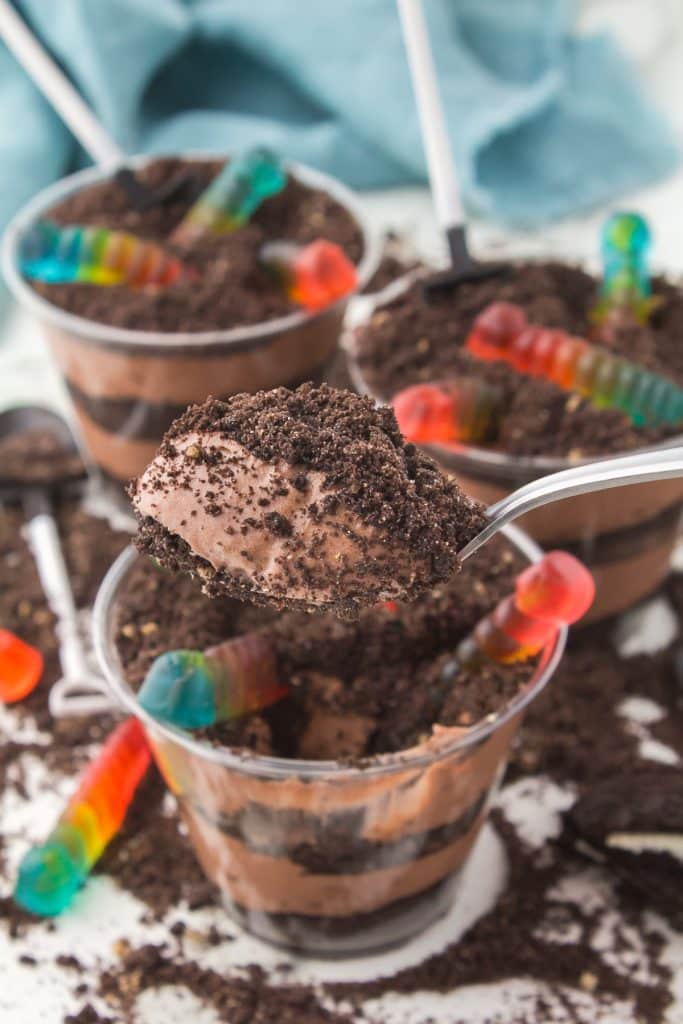 spoon lifting a bite of oreo dirt dessert from a cup.