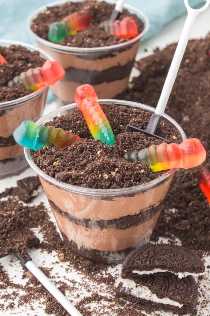 dirt cup dessert with gummy worms hanging out the top.