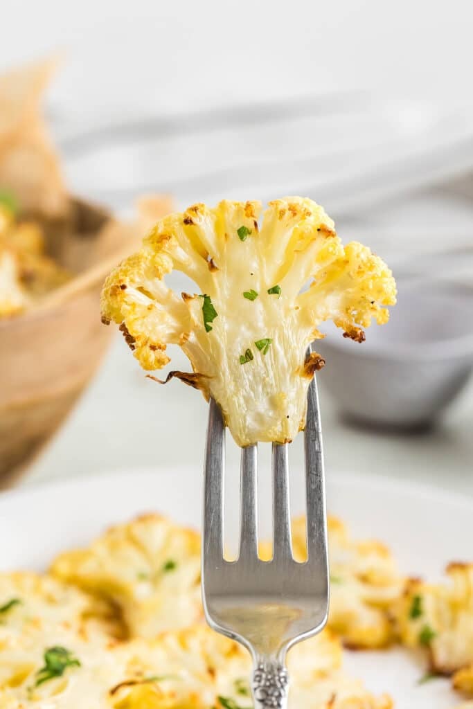 fork holding a roasted cauliflower floret.
