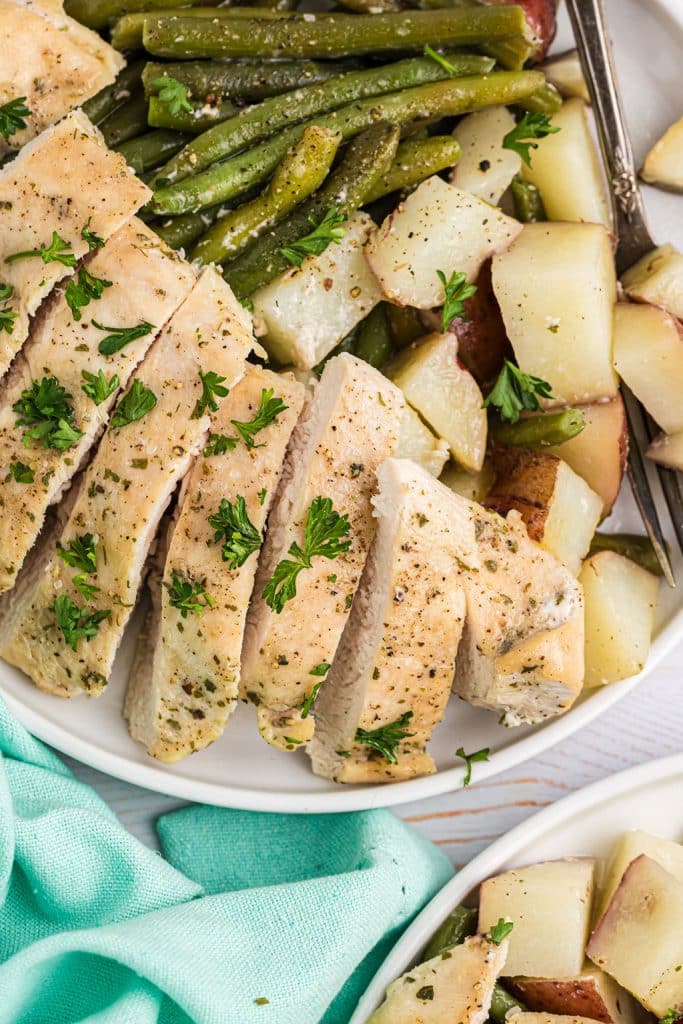 plate of sliced chicken breast with cubed potatoes & green beans.