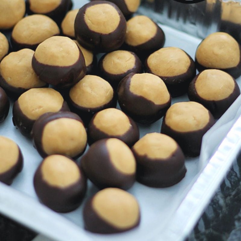 Peanut Butter Balls are a super simple, no-bake, treat that are great any time of the year. Sometimes called buckeye balls, these sweet and salty peanut butter balls are dipped into dark chocolate and are irresistible! | www.persnicketyplates.com #christmas #christmastreats #christmasdesserts #nobake #peanutbutter #chocolate #easyrecipe #dessert tray of peanut butter balls