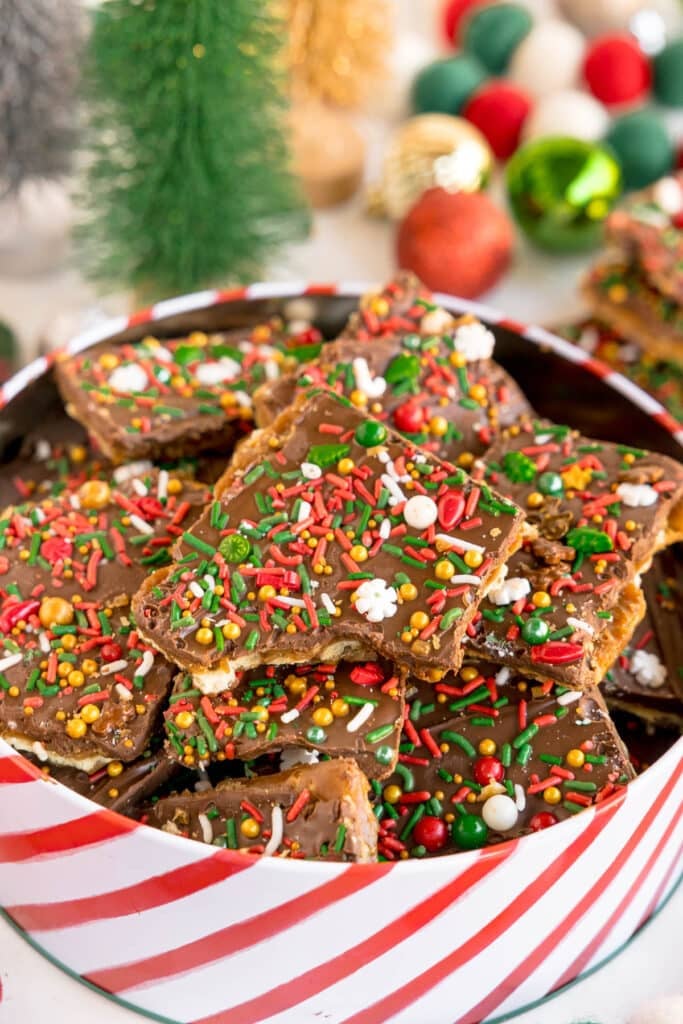 Chocolate Christmas crack with sprinkles in a striped holiday tin.