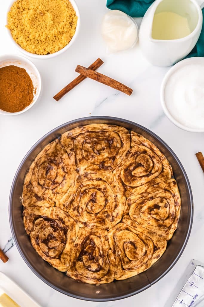 raw cinnamon rolls pressed into a springform pan to make a crust.