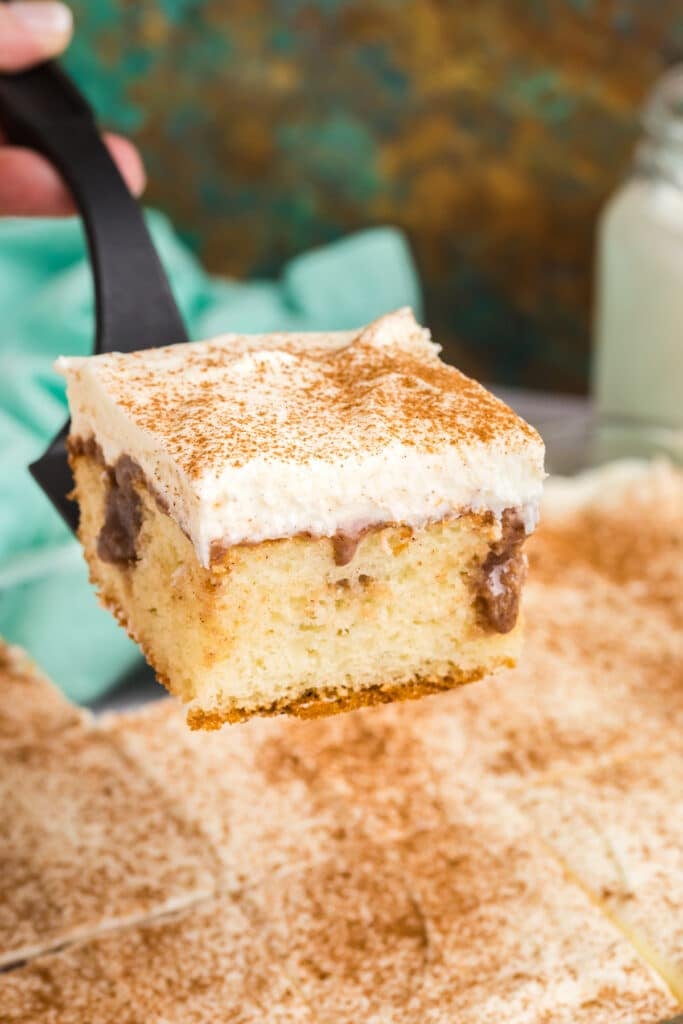 spatula lifting a slice of cinnamon roll poke cake.