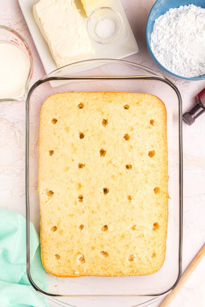 overhead shot of a white cake with holes poked in it.