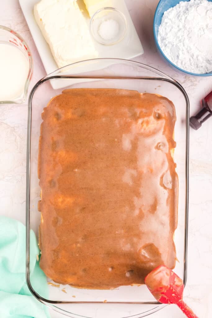 cinnamon sugar filling being spread over a poke cake.