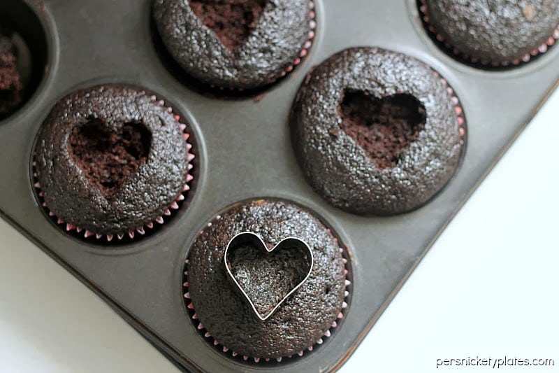 Dark chocolate cupcakes with a heart shaped cut-out filled with chocolate ganache and topped with sprinkles. Perfect for Valentine's Day!