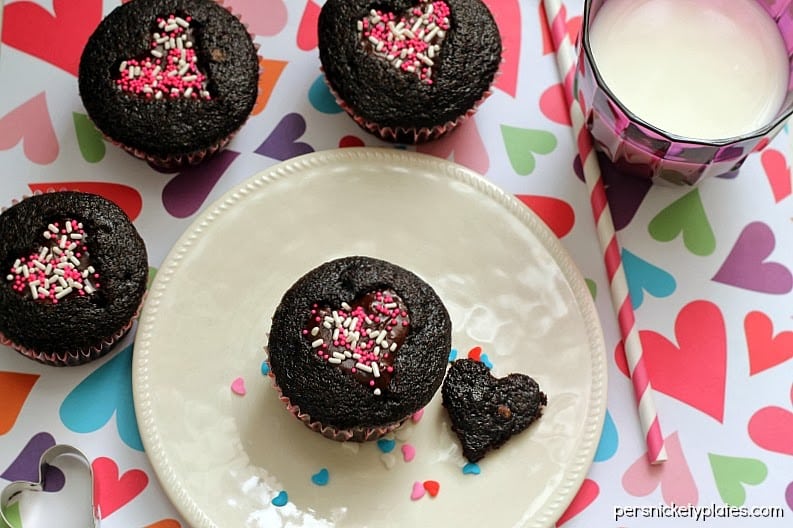 Dark chocolate cupcakes with a heart shaped cut-out filled with chocolate ganache and topped with sprinkles. Perfect for Valentine's Day!