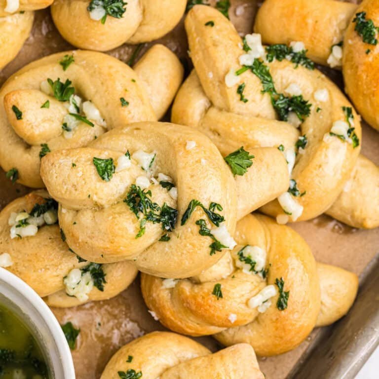overhead shot of a pile of garlic knots topped with parsley.