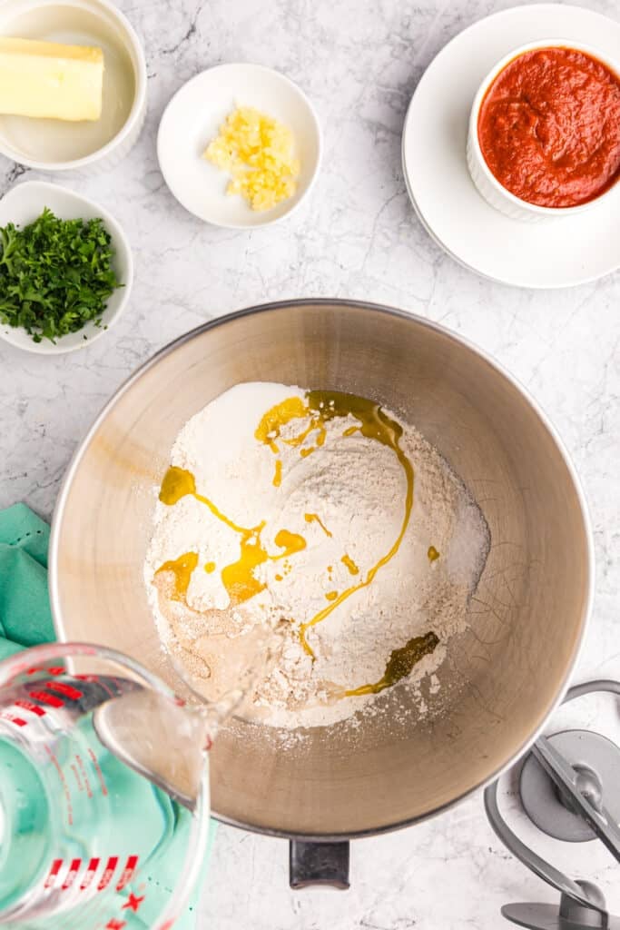 olive oil pouring into a mixing bowl of flour.