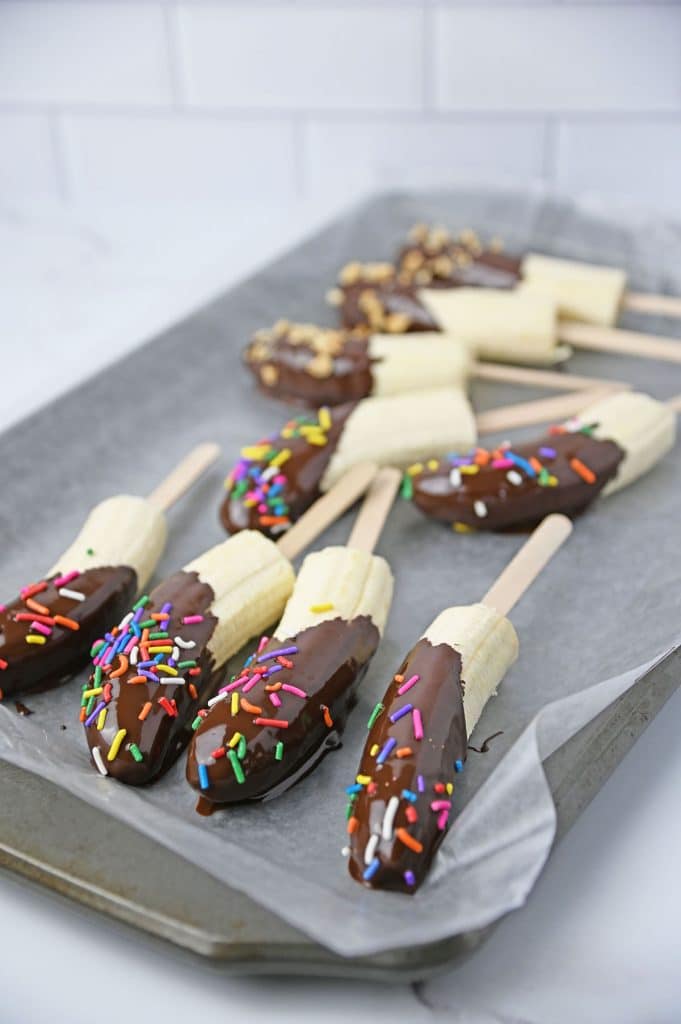 chocolate dipped bananas laying on a baking sheet.