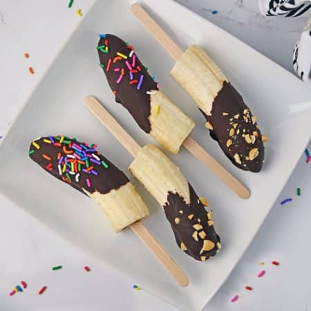 overhead shot of chocolate dipped bananas on a white plate.
