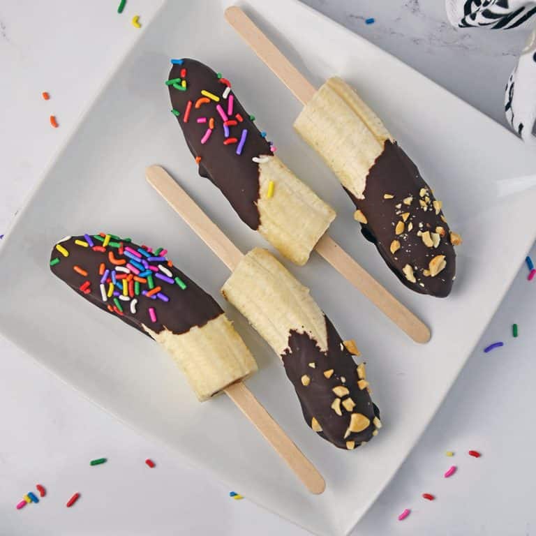 overhead shot of chocolate dipped bananas on a white plate.