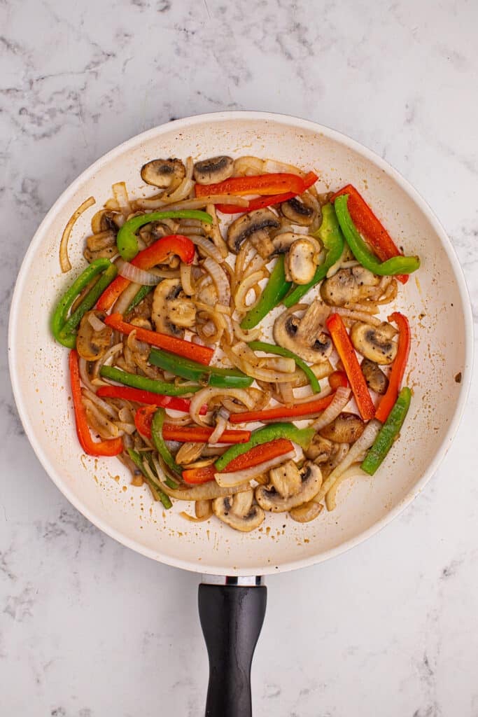 overhead shot of peppers and onions in a skillet.
