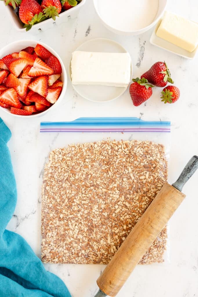 pretzels being crushed in a zip top bag with a rolling pin.