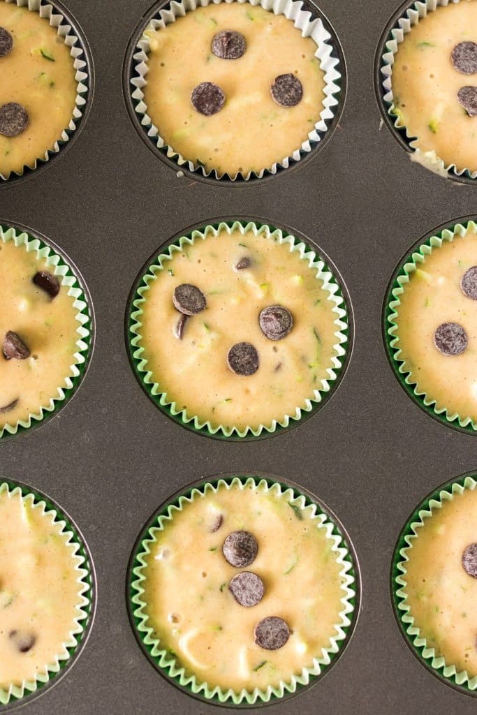overhead shot of unbaked zucchini muffins with chocolate chips on top.
