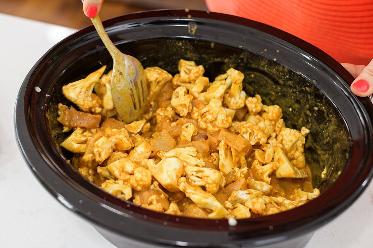 adding ingredients for indian butter chicken to slow cooker
