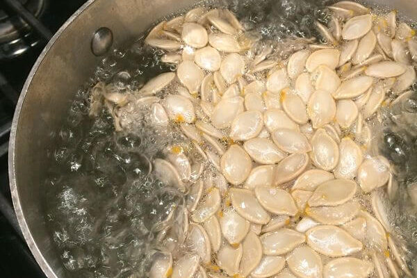 Boiling pumpkin seeds in a large pot.