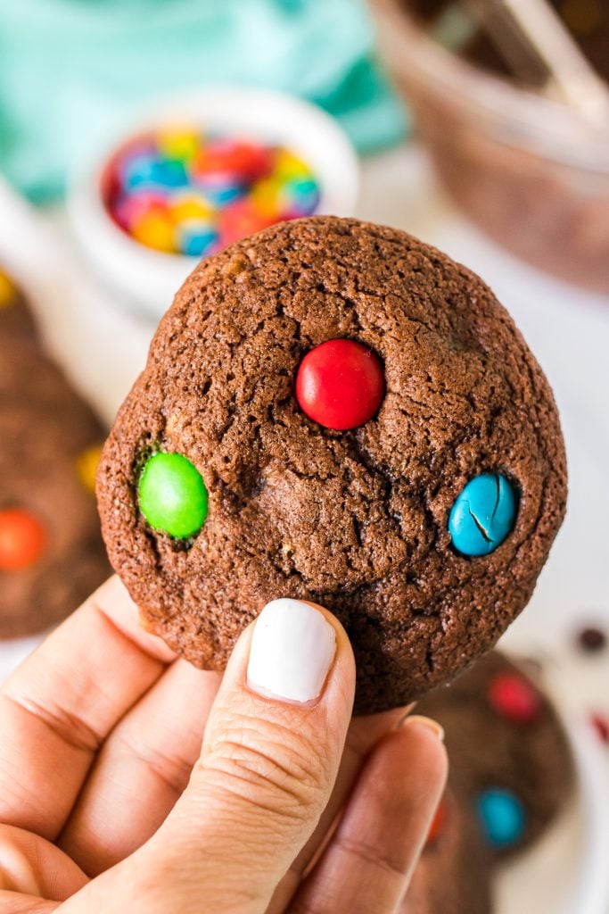 hand holding a brownie M&M cookie.