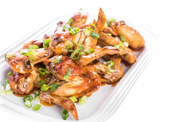plated chicken wings with scallions sprinkled on them