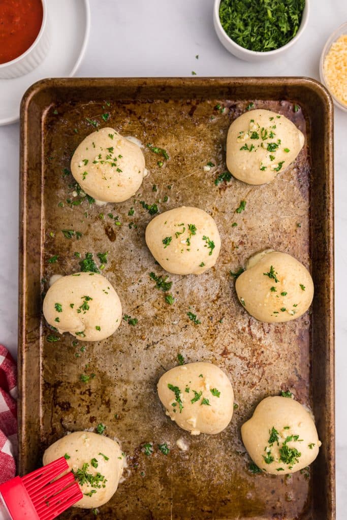 pastry brush brushing garlic butter on rolls.