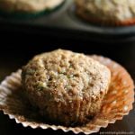 apple zucchini muffin sitting on a peeled cupcake wrapper.