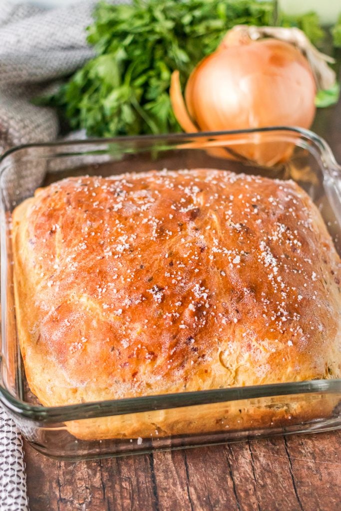 loaf of onion dill bread in baking dish