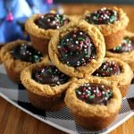 stack of peanut butter cookie cups filled with chocolate & topped with christmas sprinkles