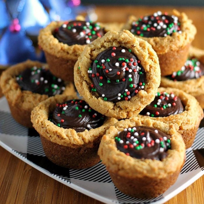 stack of peanut butter cookie cups filled with chocolate & topped with christmas sprinkles