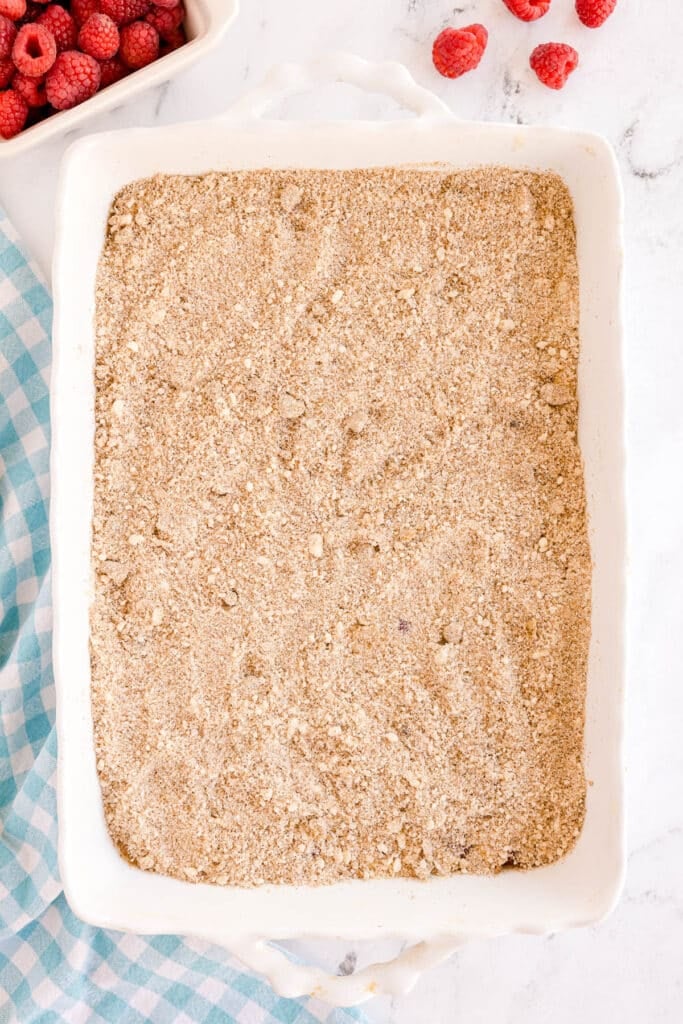 White baking dish topped with an even layer of crumb topping, ready to bake.