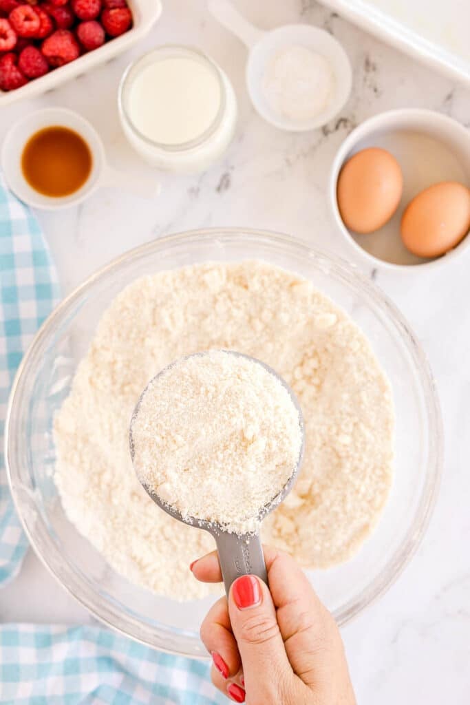 measuring cup reserving a cup of flour mixture from a mixing bowl.