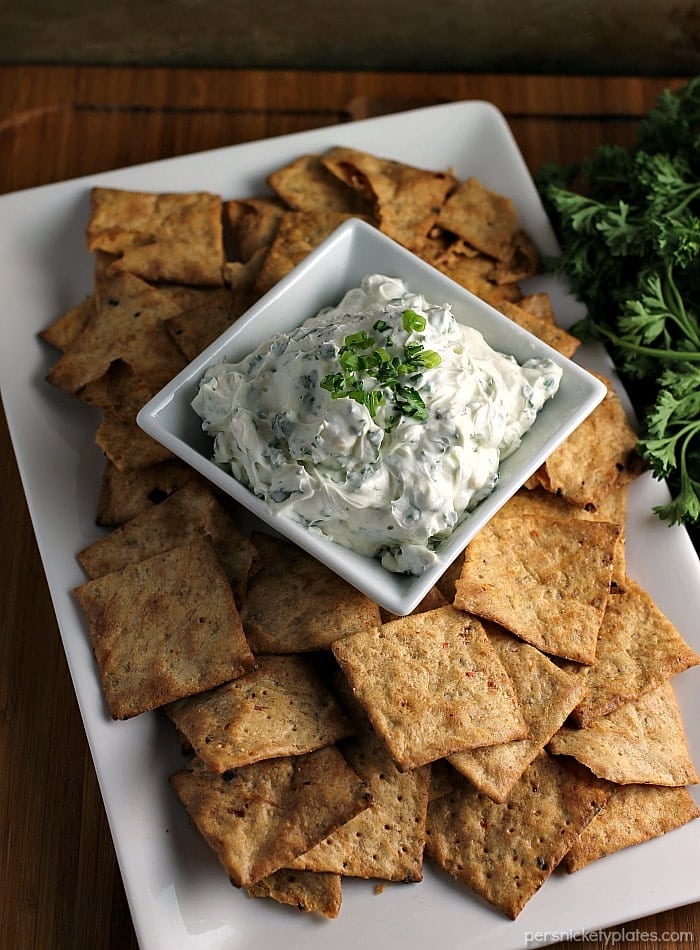 Garlic Herb Dip starts with a cream cheese base then is filled with fresh herbs. Pair this super easy dip recipe with crackers, chips, or veggies to make the perfect quick snack for your next party or game day. | www.persnicketyplates.com #dip #appetizer #easyrecipe #partyfood #garlic chips & dip on a white platter
