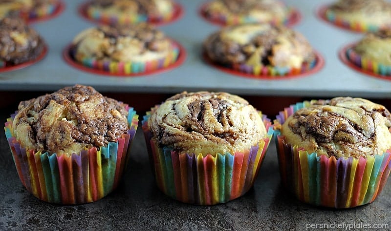 three nutella muffins lined up with muffin tray in background