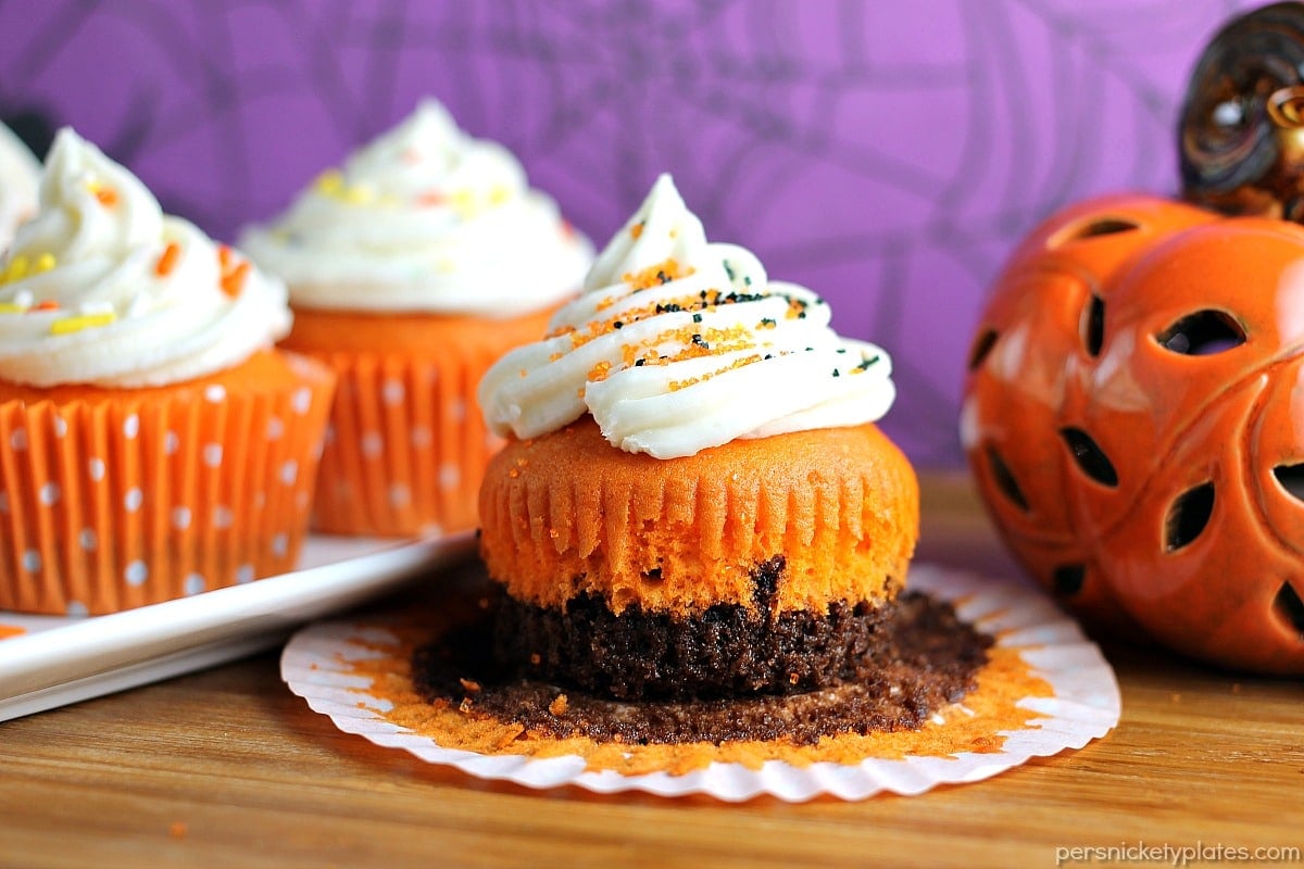 Brownie Bottom Halloween Cupcakes have a layer of dark chocolate brownie topped with orange cake batter and finished off with buttercream and sprinkles. They are the perfect mix of semi-homemade and "from scratch" to be easy but really fun and festive for your next Halloween party! | Persnickety Plates