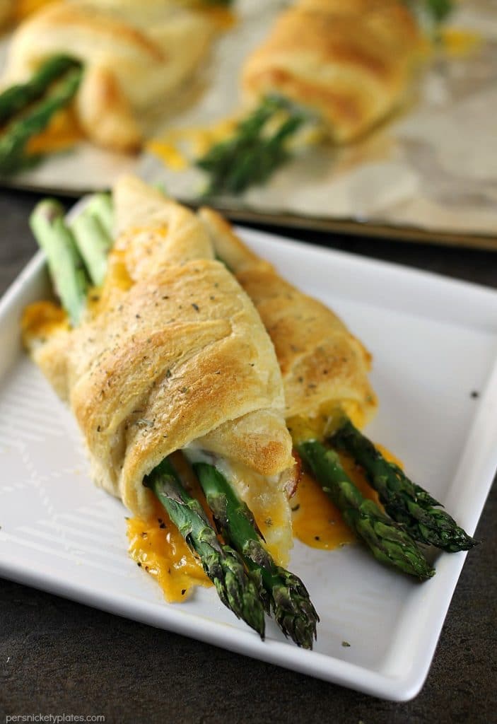 two cheesy asparagus puffs on a white plate