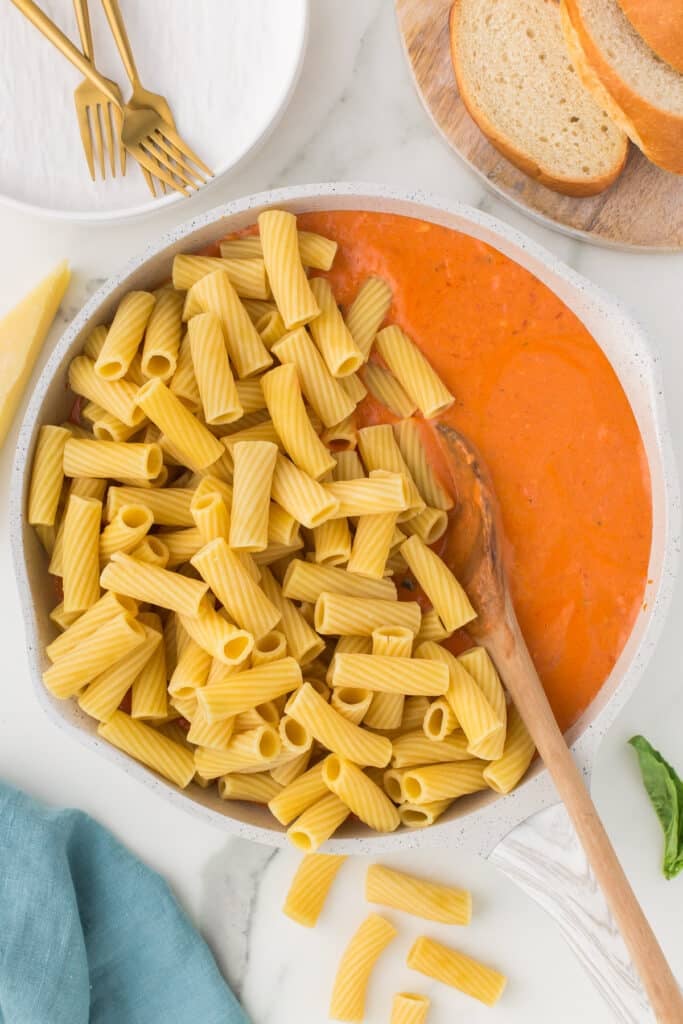 cooked rigatoni being stirred into vodka sauce.