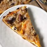 Peach Crumble Fruit Pizza is made on a cake batter crust, piled with thinly sliced fresh peaches and topped with a crumble and pecans and drizzled with a cinnamon sugar glaze. | www.persnicketyplates.com