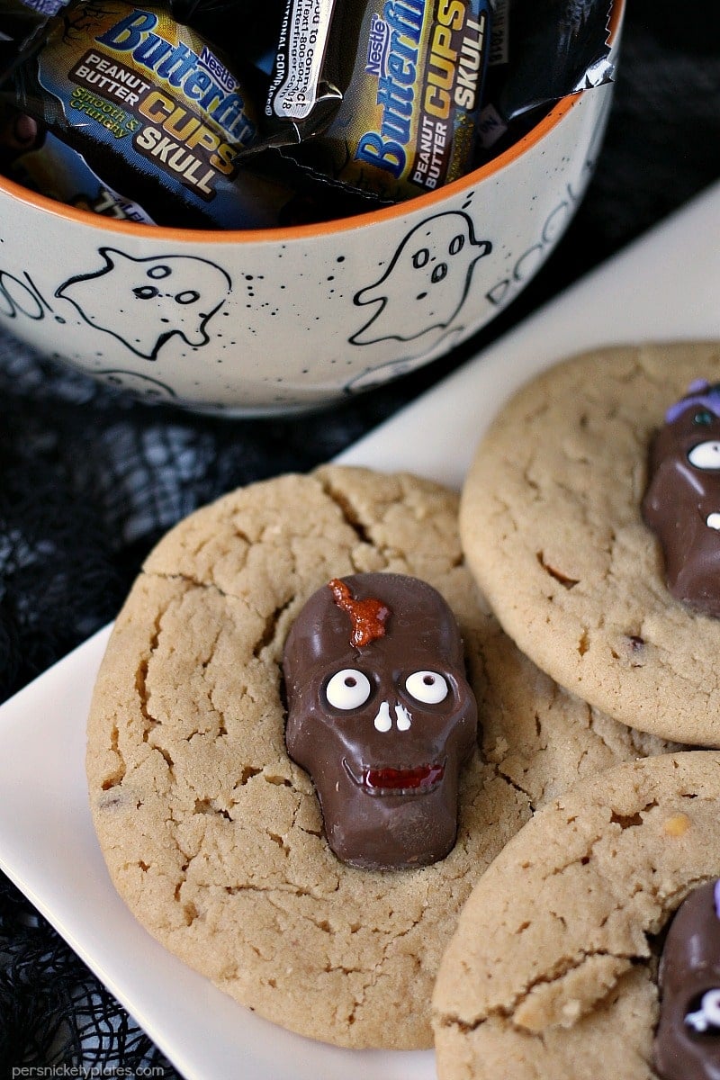 Peanut Butter Butterfinger Skull Cookies start with a soft and chewy from scratch peanut butter cookie then are topped with a spooky, decorated Butterfinger Peanut Butter Skull Cup. Perfect for any Halloween party! | www.persnicketyplates.com