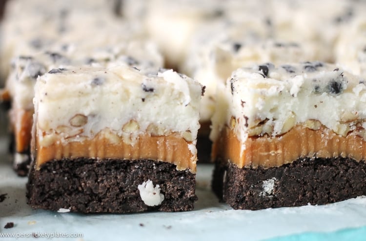 Cookies and Cream Caramel Layer Bars start with a layer of Pillsbury Cookies 'n Creme cookie dough, topped with a layer of caramel, chopped pecans, frosting, then finished with melted Cookies 'n Creme candy bars. I hope your sweet tooth is ready! close up of cookies and cream caramel layer bars