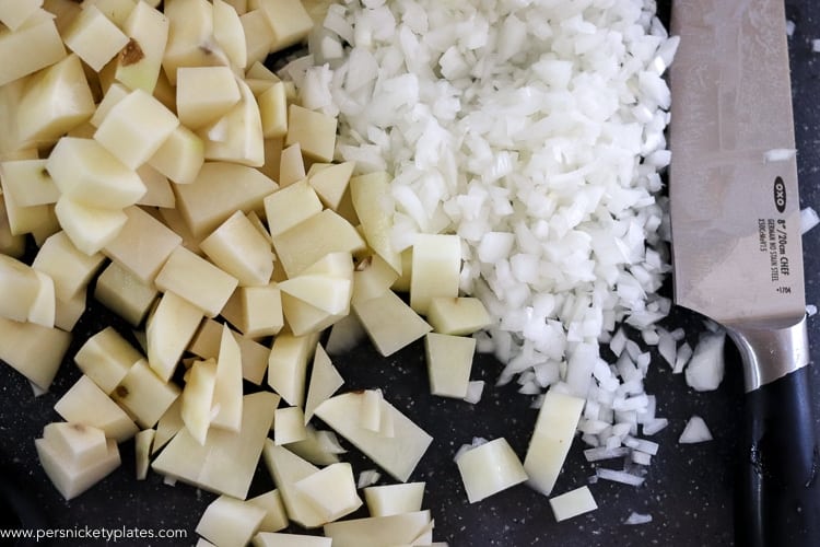 Loaded Potato and Cauliflower Soup has everything you love about loaded potato soup - it's creamy, full of smoky bacon, and cheese - but is lightened up with the use of cauliflower! | www.persnicketyplates.com chopped potatoes and onions with an oxo pro chef's knife