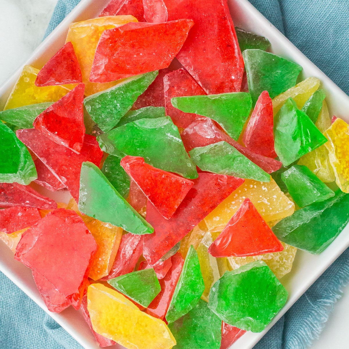 overhead shot of red, green, & yellow hard candy on a plate.