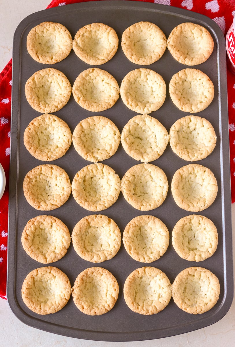 Valentine Sugar Cookie Cups are a simple, semi-homemade treat that you can whip up in no time! A sugar cookie base filled with pink frosting and topped with Valentine sprinkles. | www.persnicketyplates.com