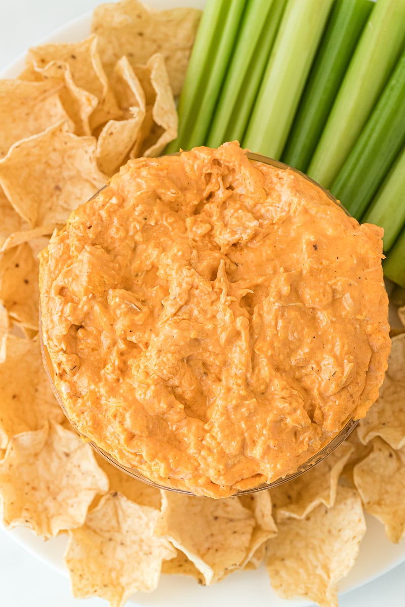 overhead shot of buffalo chicken dip on a platter with chips & celery