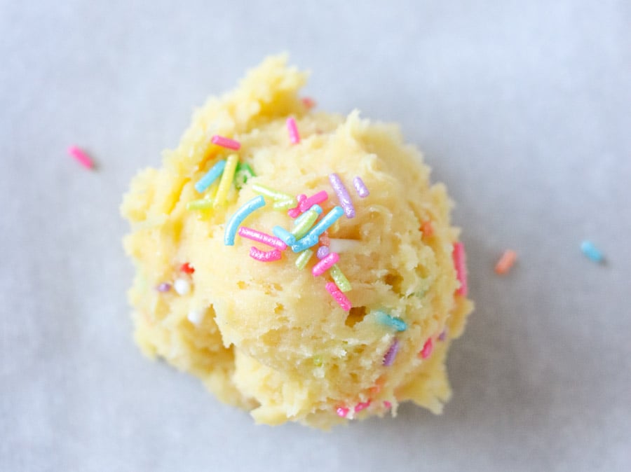 close up of cookie dough ball with rainbow sprinkles